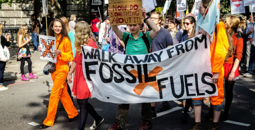 Young people on a climate march holding a streamer “Walk away from fossil fuels”