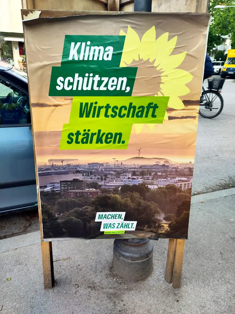 Afb: een billboard met de tekst - Bescherm het Klimaat, Versterk de Economie: Doen wat Telt, zoals te zien in de straten van München.